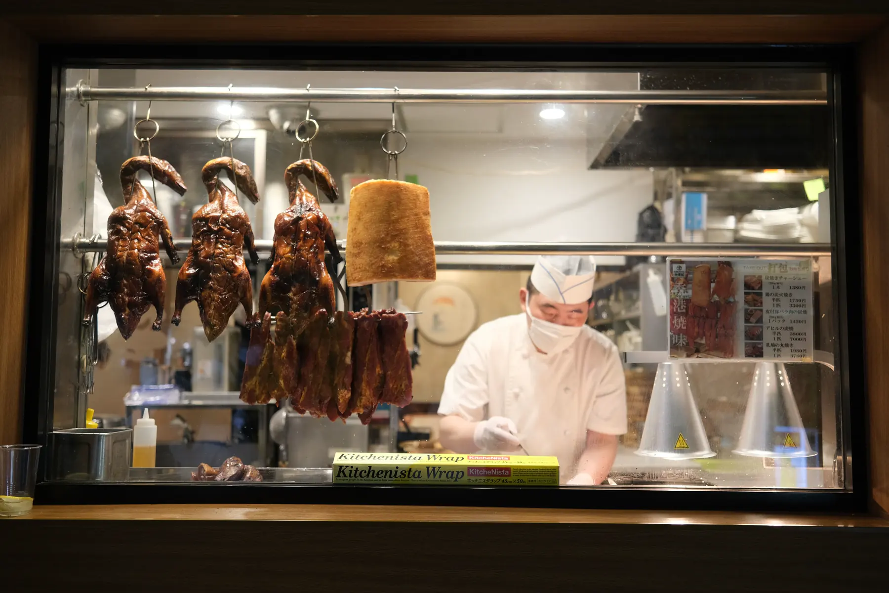 Roast ducks hanging behind a restaurant window