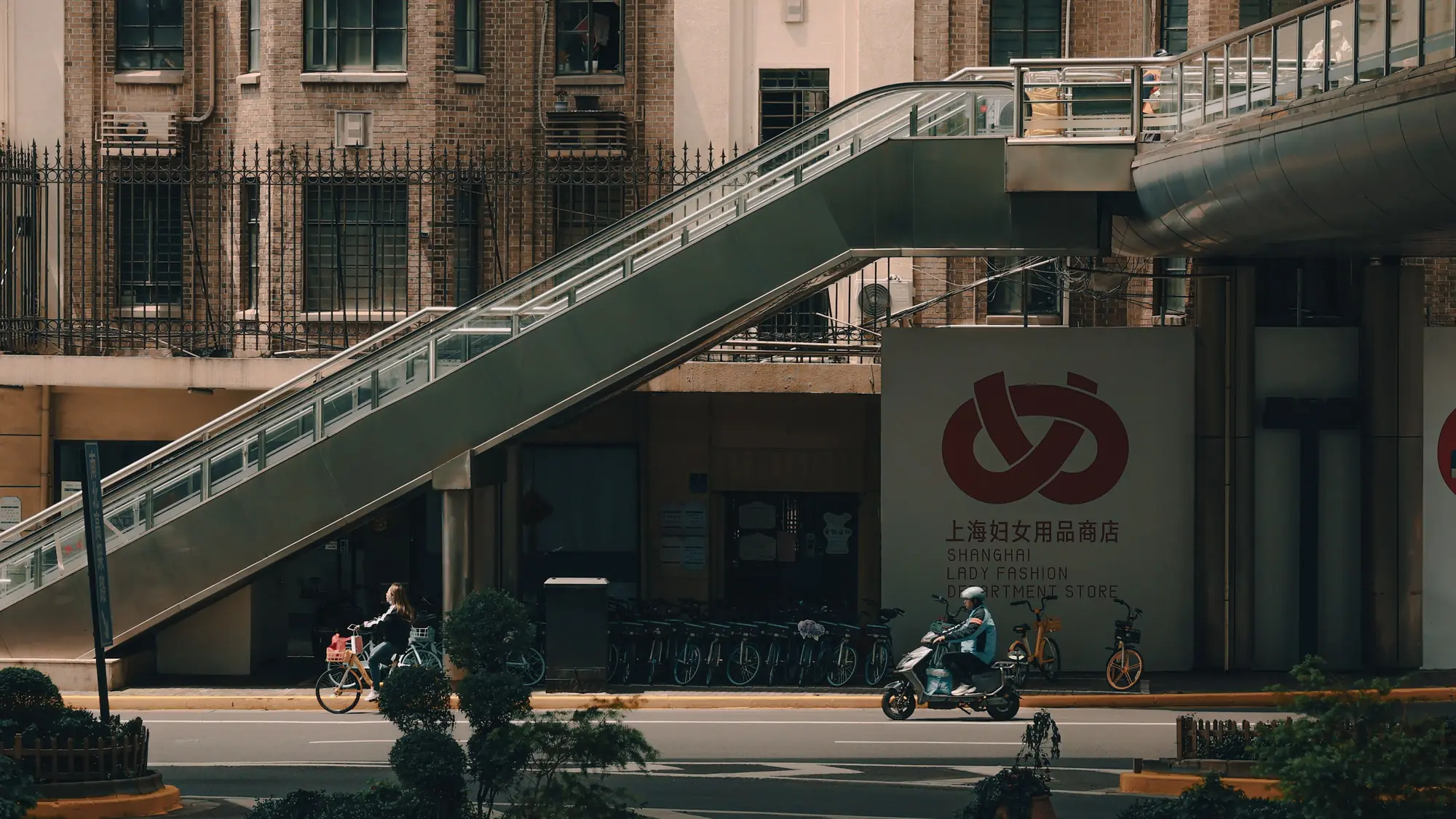 An outdoor escalator crossing above a Shanghai street