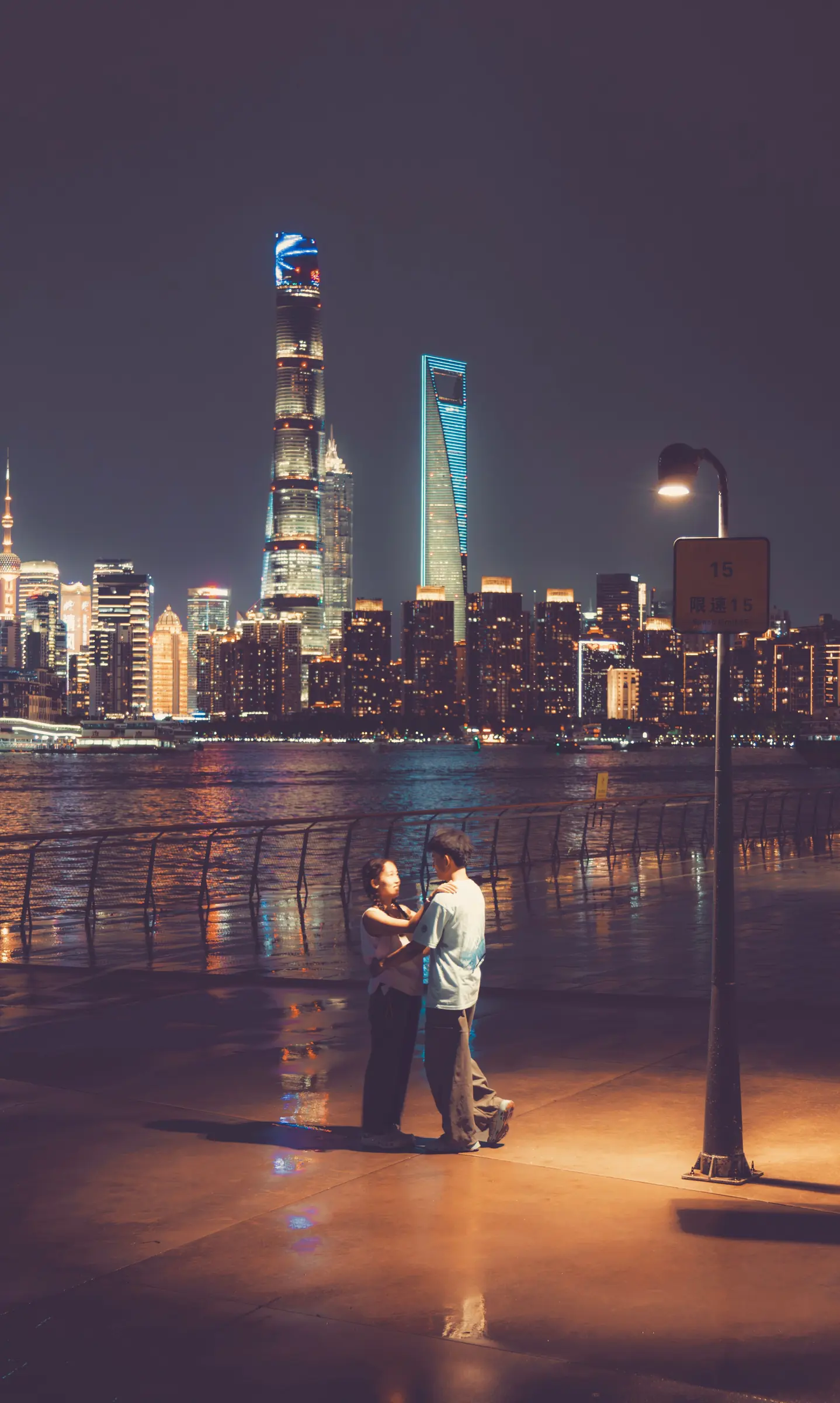 Two people meeting on Shanghai’s waterfront beneath the Pudong skyline
