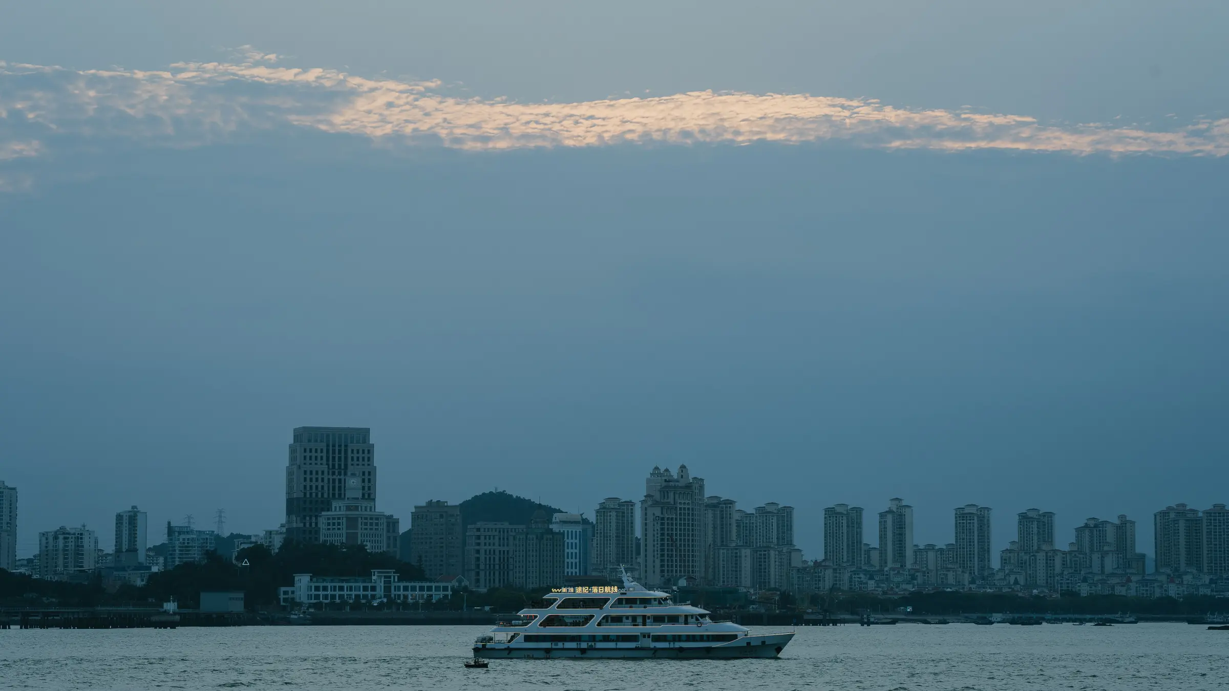 A ferry moving in front of Xiamen's waterfront skyline