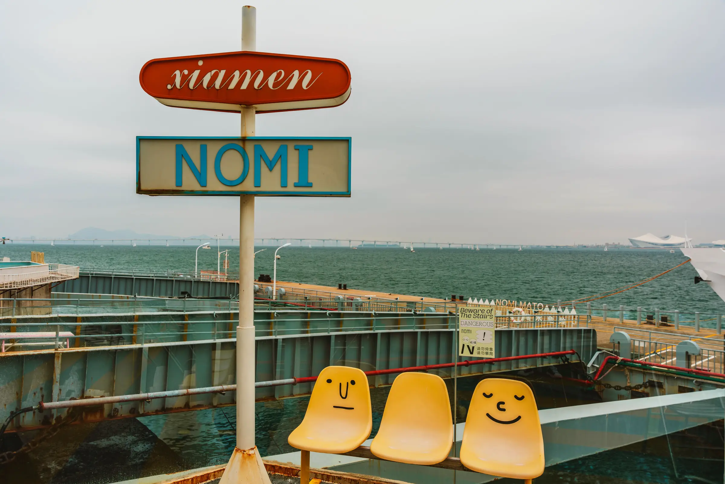 A playful Xiamen sign and yellow seats beside the sea