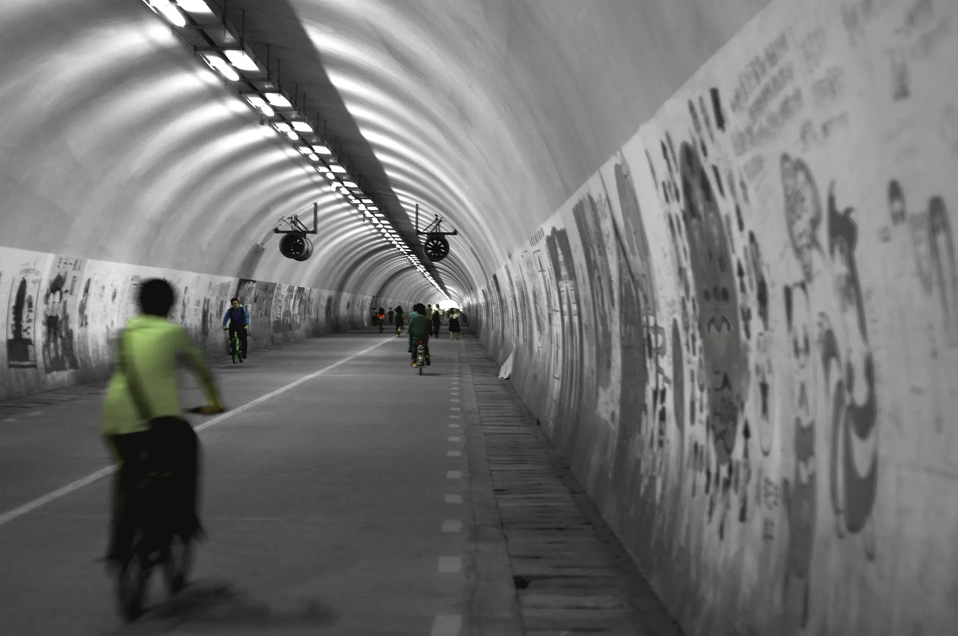Cyclists moving through a monochrome tunnel in Xiamen