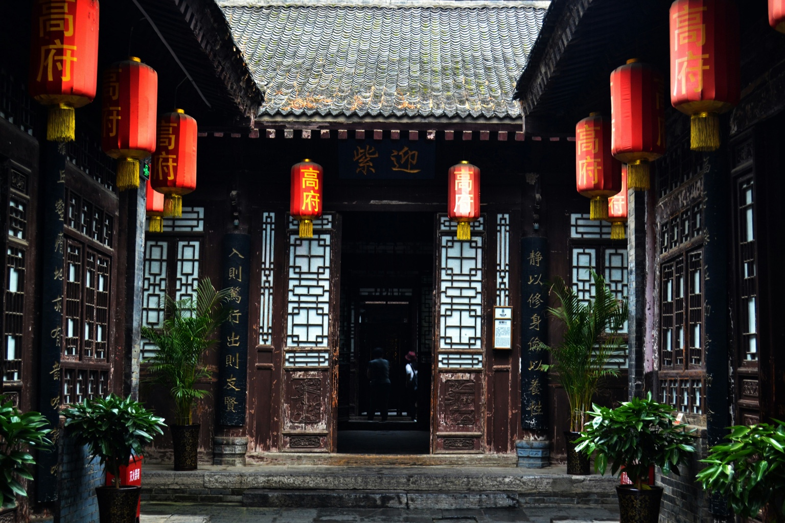 A timber courtyard lined with calligraphy and red lanterns