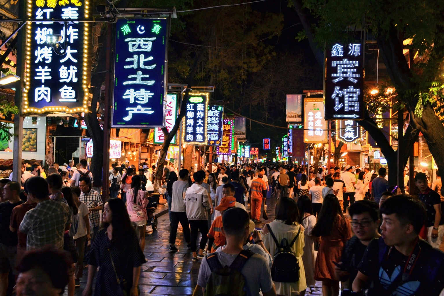 A crowded Xi’an night market filled with illuminated food signs
