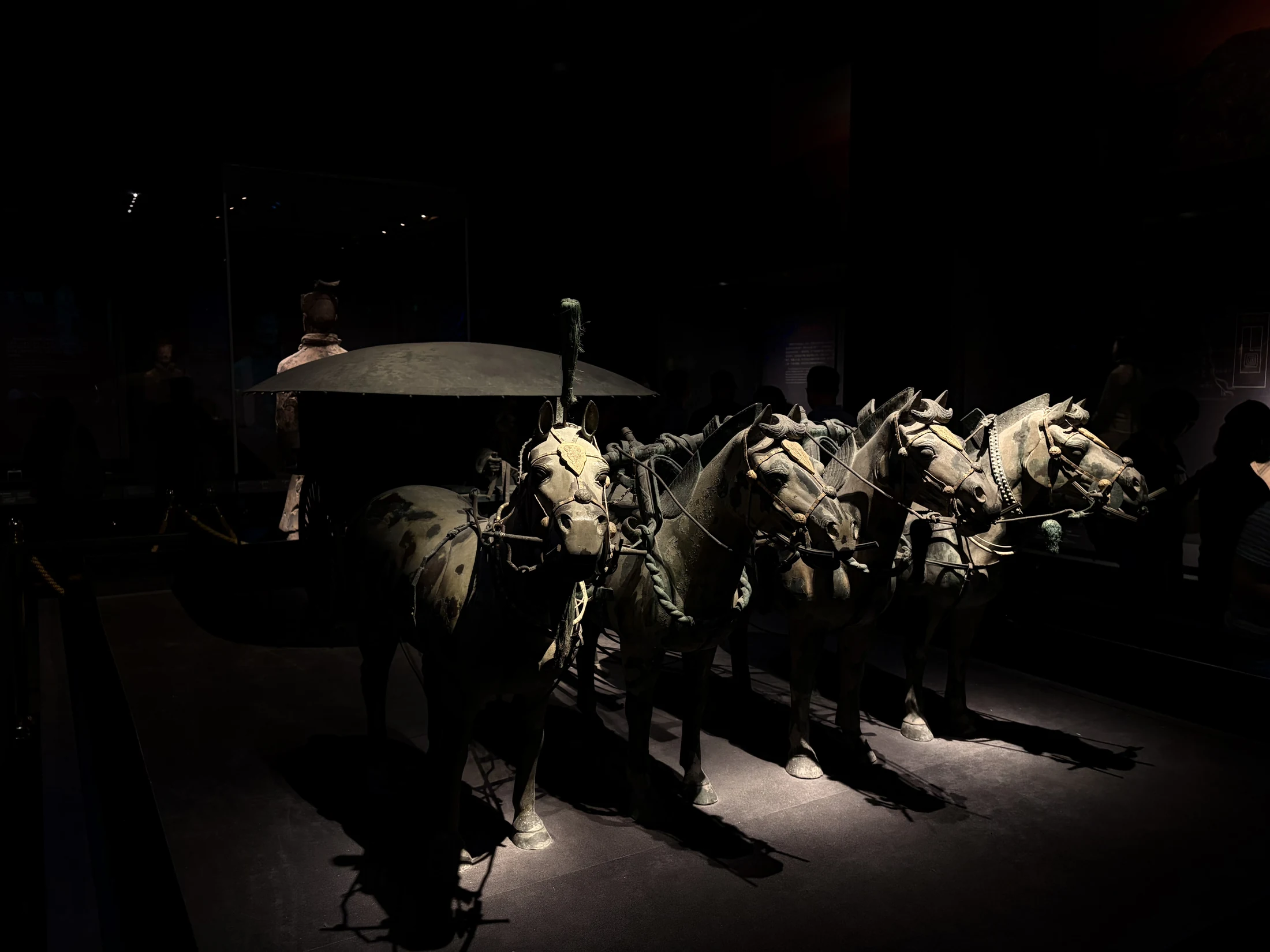 A bronze chariot drawn by four horses under focused museum light