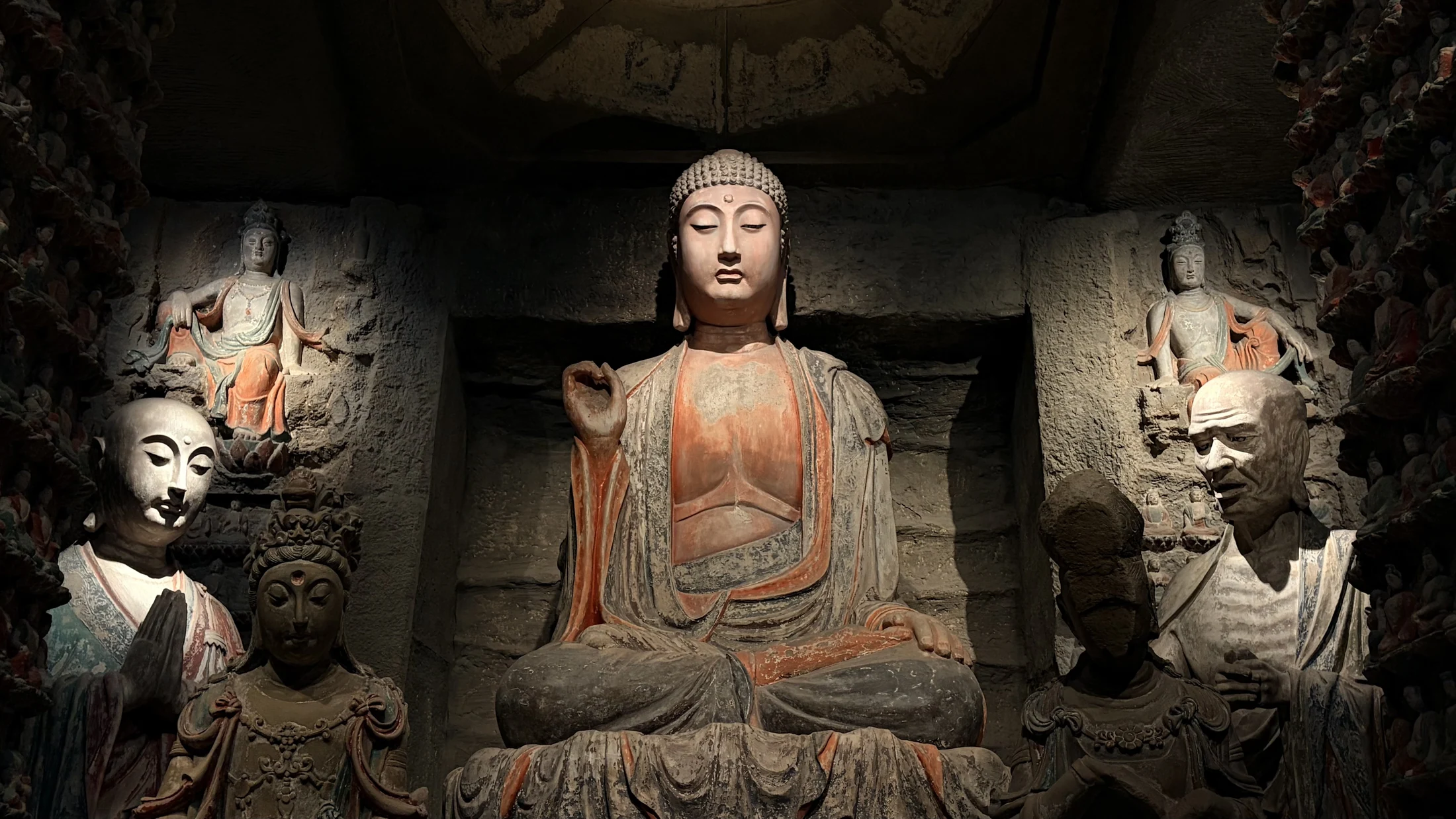 A Buddhist shrine ensemble with a central seated figure and attendant sculptures