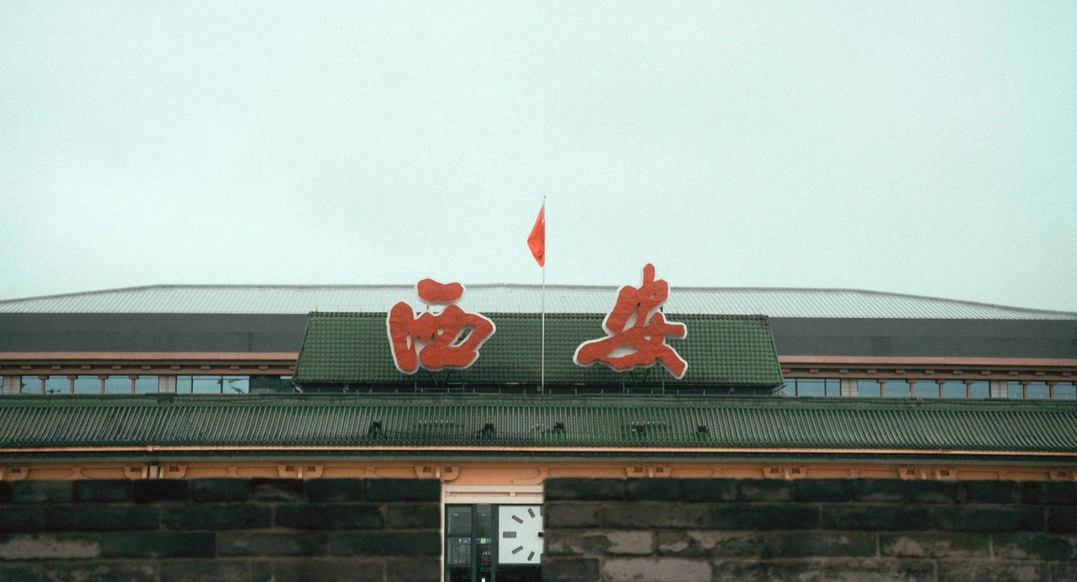 Xi’an railway station sign and clock rising behind the historic city wall