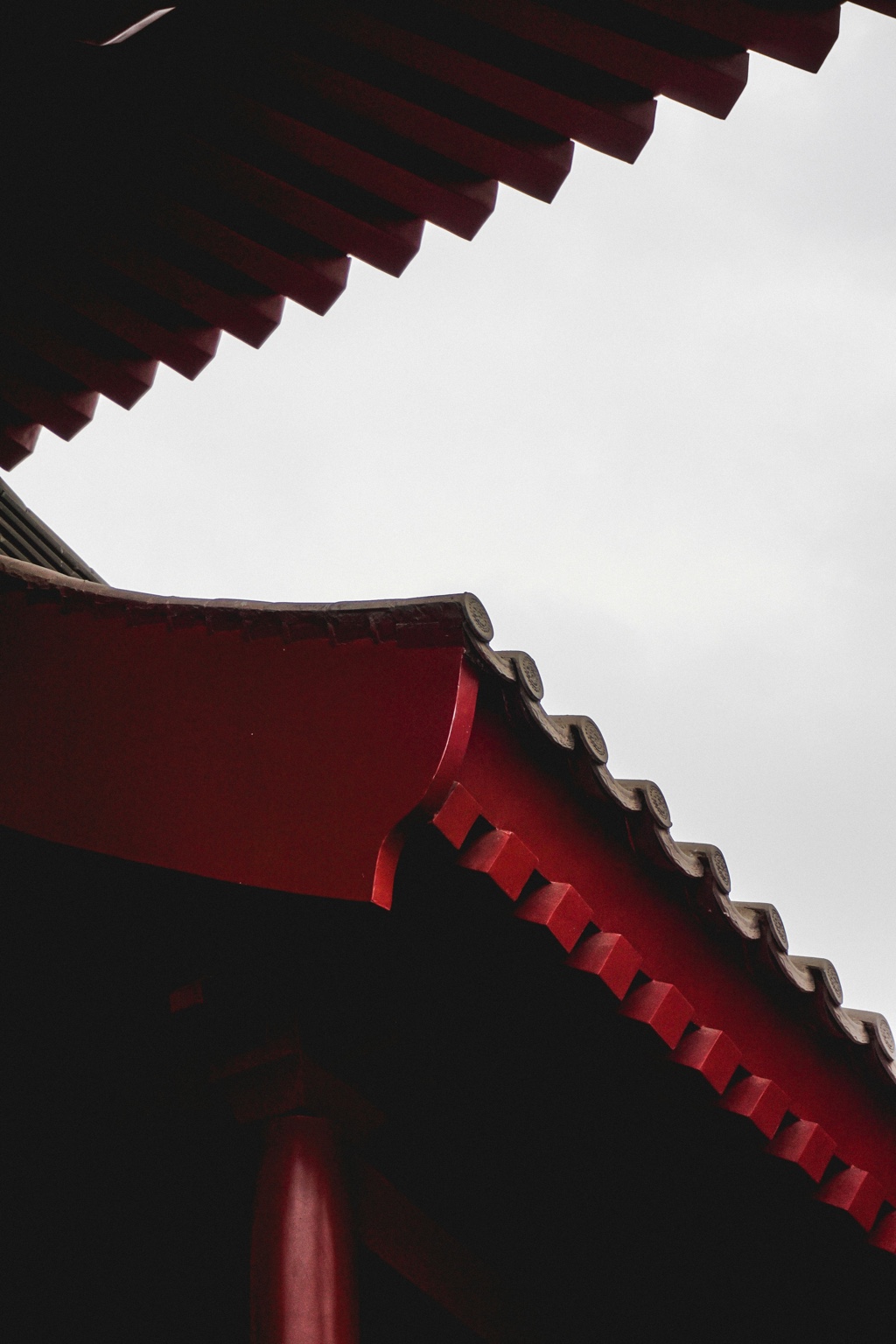 Red-painted traditional eaves framing a pale sky