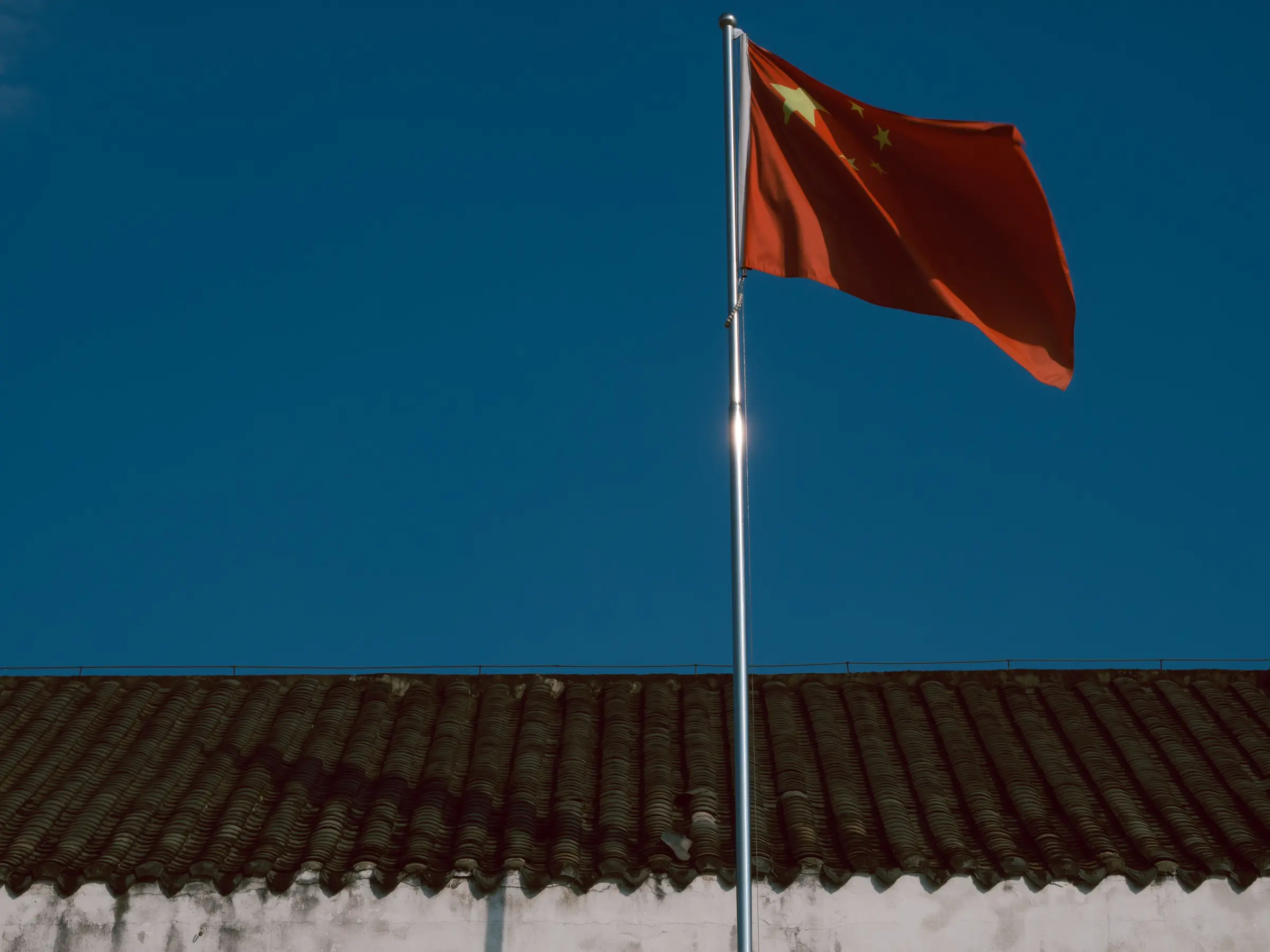 A Chinese flag above a traditional tiled roof