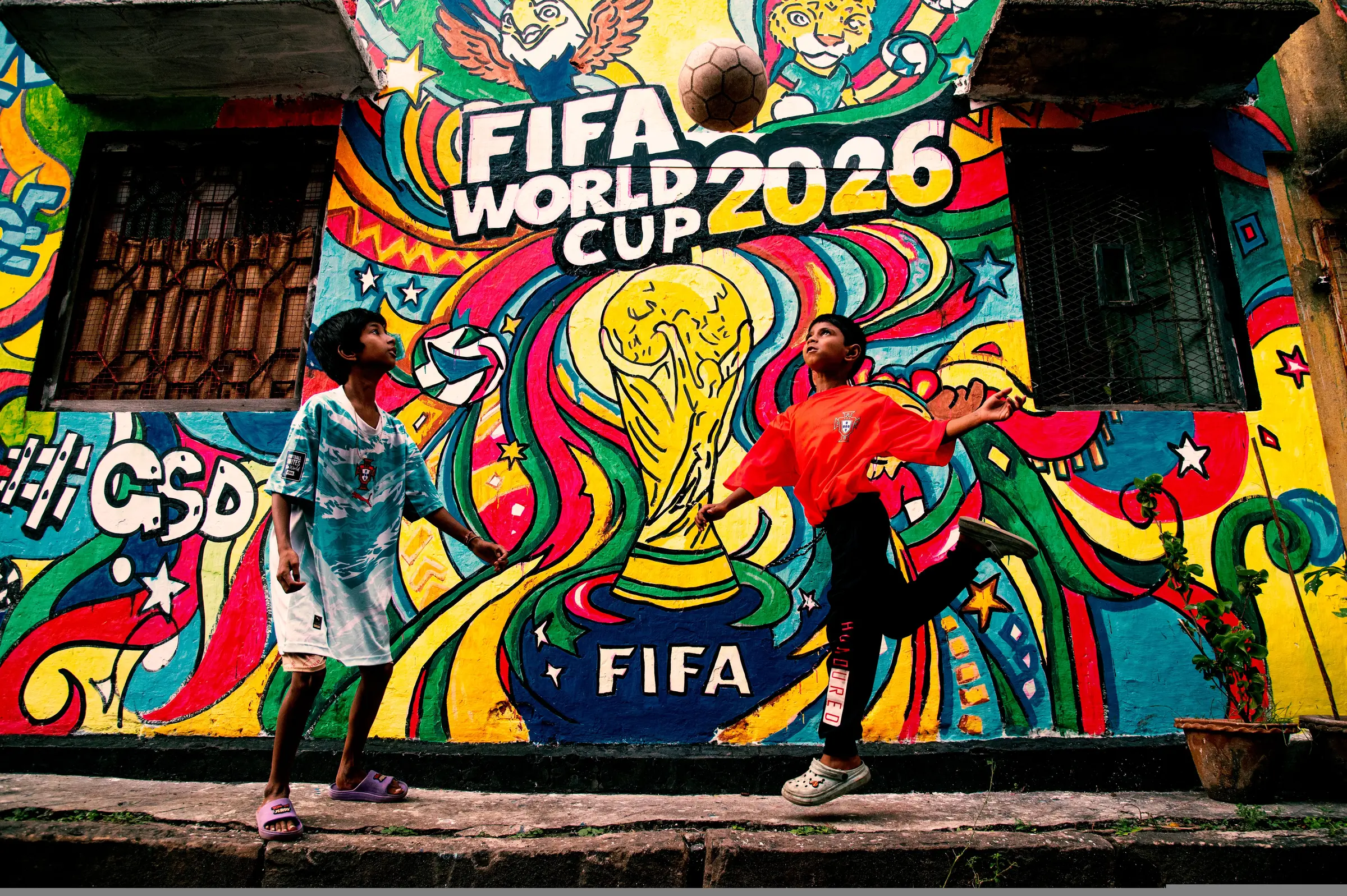 People gathered beside a colourful World Cup mural