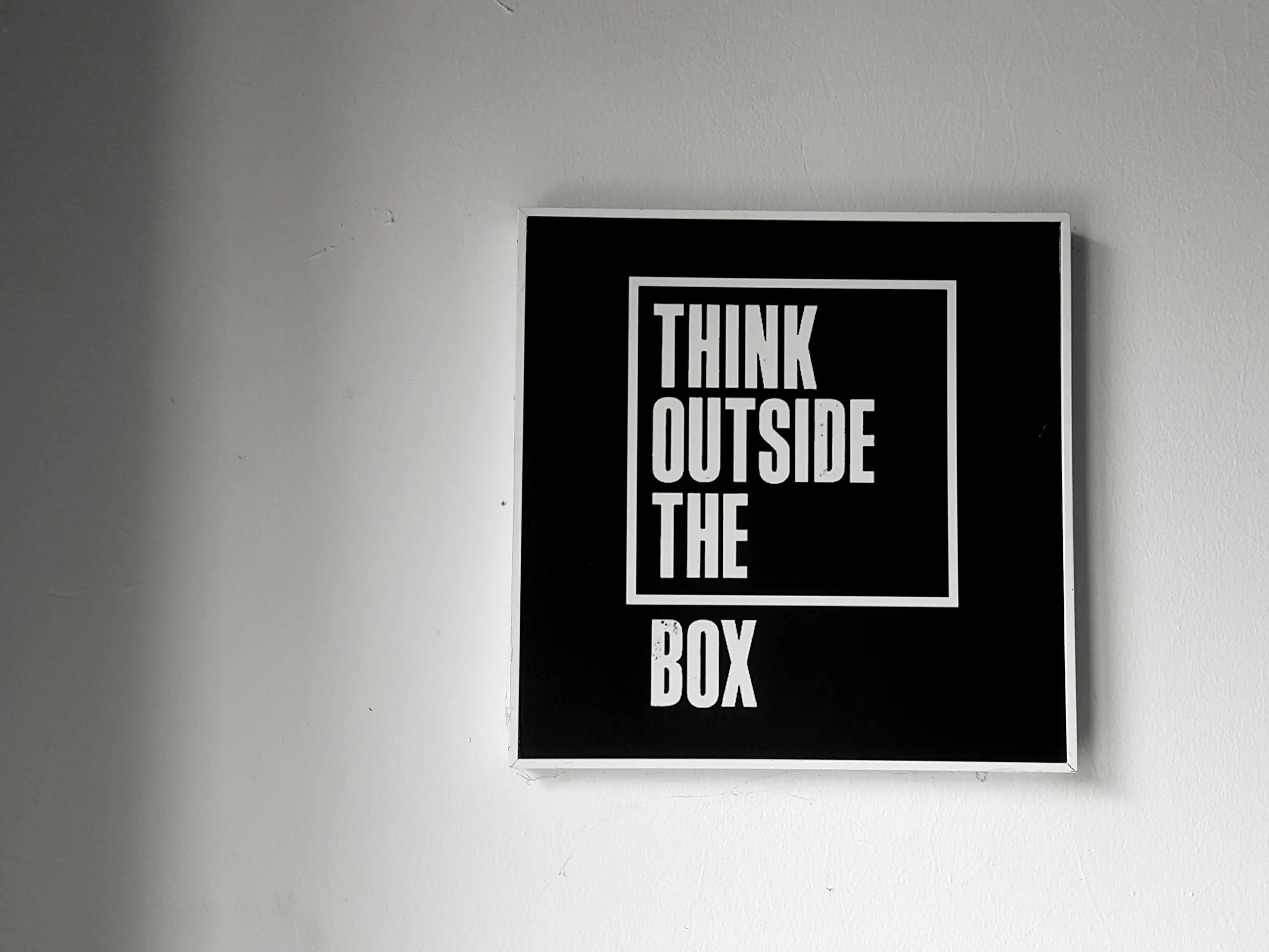 A framed sign reading Think Outside the Box